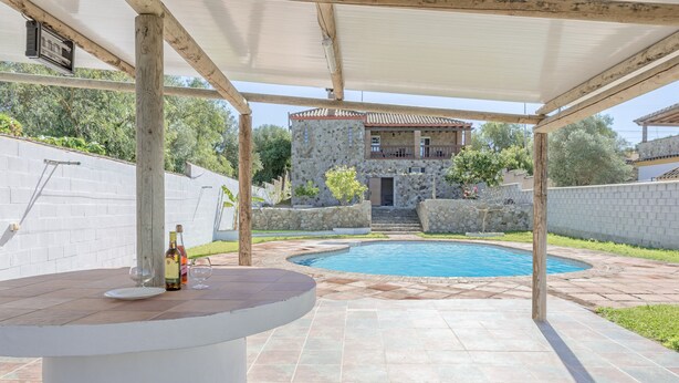 Un espace extérieur abrité avec une piscine, des murs en pierre et un bâtiment en arrière-plan.