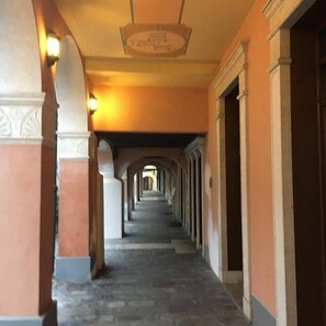 Un pasillo con arcos, columnas y una lámpara en el techo.