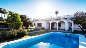 A swimming pool with a tiled edge, a white building with arches, and a clear sky. - Air-Conditioned Home On the Beach with Pool, Terrace, Garden & Wi-Fi (Torremolinos)