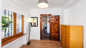 A hallway with a wooden bench, a floor lamp, a wooden door, and a view through a window with metal bars. - Air-Conditioned Home On the Beach with Pool, Terrace, Garden & Wi-Fi (Torremolinos)