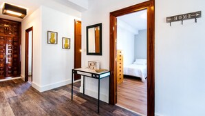 A hallway with a wooden door, a table with a mirror, and a bed in the adjacent room. - Air-Conditioned Home On the Beach with Pool, Terrace, Garden & Wi-Fi (Torremolinos)