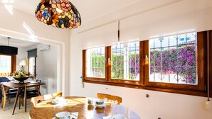 A dining area with a wooden table, chairs, and a stained glass light fixture. - Air-Conditioned Home On the Beach with Pool, Terrace, Garden & Wi-Fi (Torremolinos)