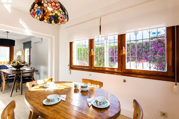 A dining area with a wooden table, chairs, and a stained glass light fixture.