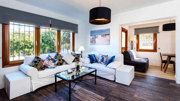 A modern living room with a white sofa, a glass coffee table, and a black pendant light. - Air-Conditioned Home On the Beach with Pool, Terrace, Garden & Wi-Fi (Torremolinos)