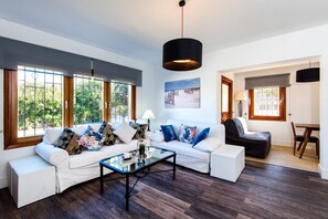 A modern living room with a white sofa, a glass coffee table, and a black pendant light.