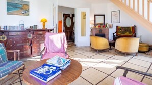 A living room with a round coffee table, a sofa, and a chair. There is a fireplace with a mirror above it. - Sunny Lodge by Interhome (Cabourg)