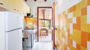 A kitchen with a refrigerator, stove, and wooden cabinets. - Quietly Situated Holiday Home with Sea View, Garden & Terrace (Arzachena)