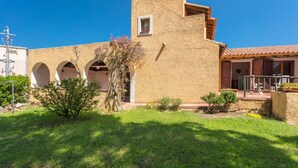 A building with a courtyard, a small tree, and a clear blue sky. - Quietly Situated Holiday Home with Sea View, Garden & Terrace (Arzachena)