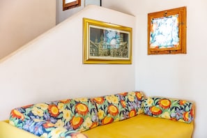 A room with a sofa, a framed picture on the wall, and a window with a view.