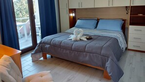 Ein Schlafzimmer mit einem Bett, einem Holz-Kopfteil, einem Nachttisch, einem Schreibtisch und einem Fenster mit Vorhängen.