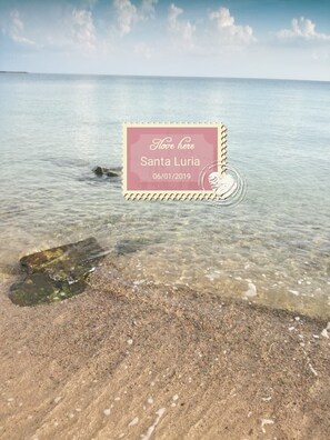 A postcard with 'I love here Santa Luria' and a date '06/01/2019' on a beach scene.