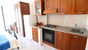 Una cocina con armarios de madera, una estufa a gas, un fregadero y un refrigerador.