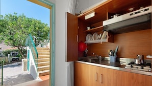Una cocina con armarios de madera, un lavamanos de acero inoxidable y una estufa.
