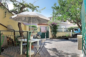Eine Terrasse mit Tisch und Stühlen, einem weißen Sonnenschirm und einem Fahrrad.