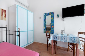 A room with a bed, a table with chairs, a TV, and a wardrobe.