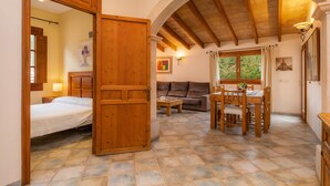 Una habitación con cama, puerta de madera, mesa de comedor y sofá.