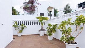 A white building with a tiled patio, potted plants, and a lamp post. - Beautiful Villa Eris with Wi-Fi, Garden, Terrace & Pool (PUERTO DEL CARMEN)
