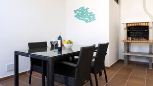 A dining area with a glass table, wicker chairs, a bowl of fruit, and a decorative wall piece. - Beautiful Villa Eris with Wi-Fi, Garden, Terrace & Pool (PUERTO DEL CARMEN)
