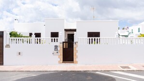 A white building with a gated entrance, a small balcony, and a flag on top. - Beautiful Villa Eris with Wi-Fi, Garden, Terrace & Pool (PUERTO DEL CARMEN)