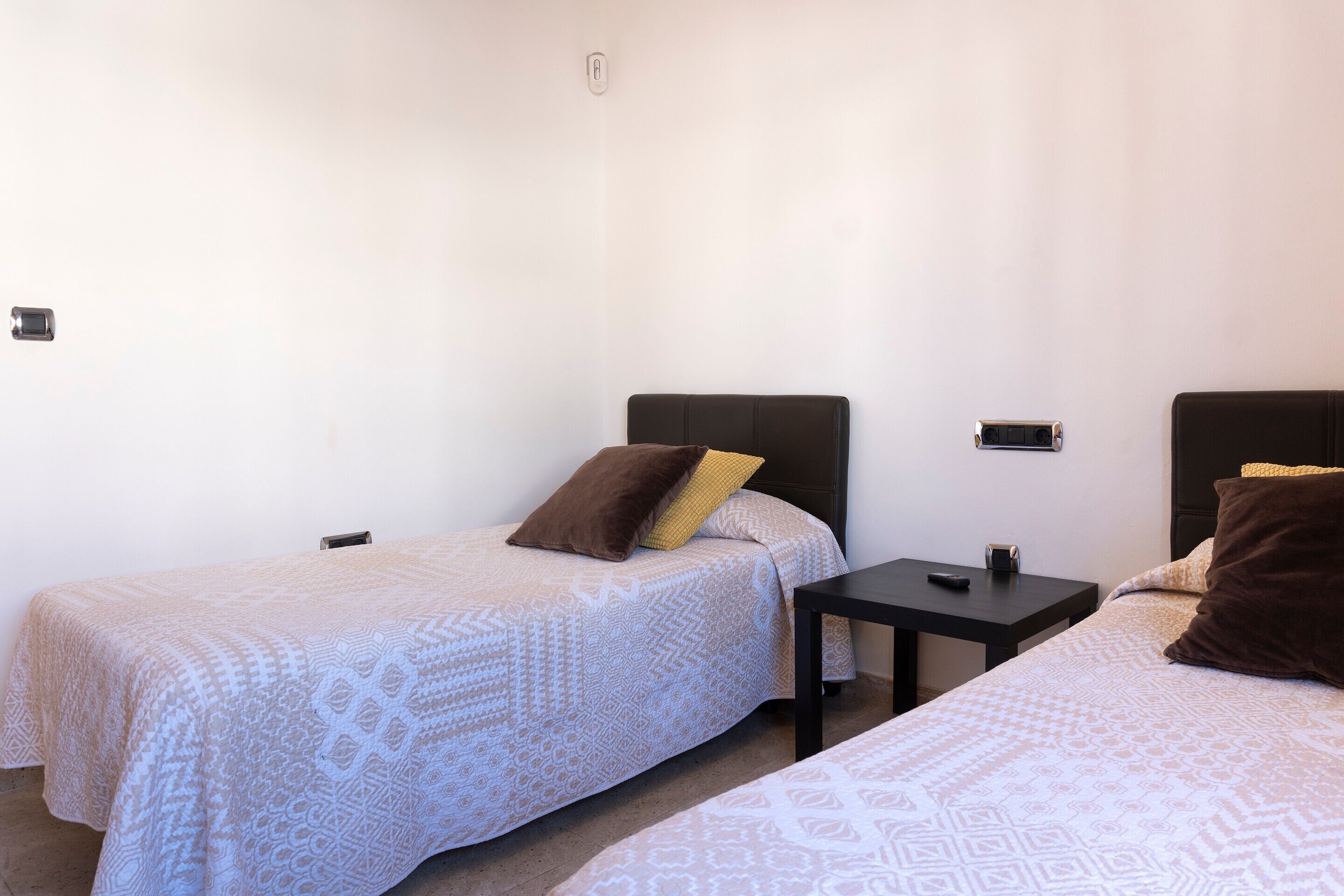 Ein Zimmer mit zwei Betten, jeweils mit Kopfteil und Nachttisch.