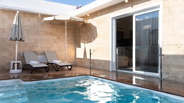 A swimming pool with lounge chairs, a covered seating area, and a glass door leading to a room. - Beautiful Villa Eris with Wi-Fi, Garden, Terrace & Pool (PUERTO DEL CARMEN)
