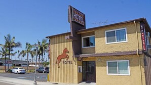 Un edificio de dos pisos con un letrero que dice "HOLLY CREST HOTEL" y un logo de caballo.