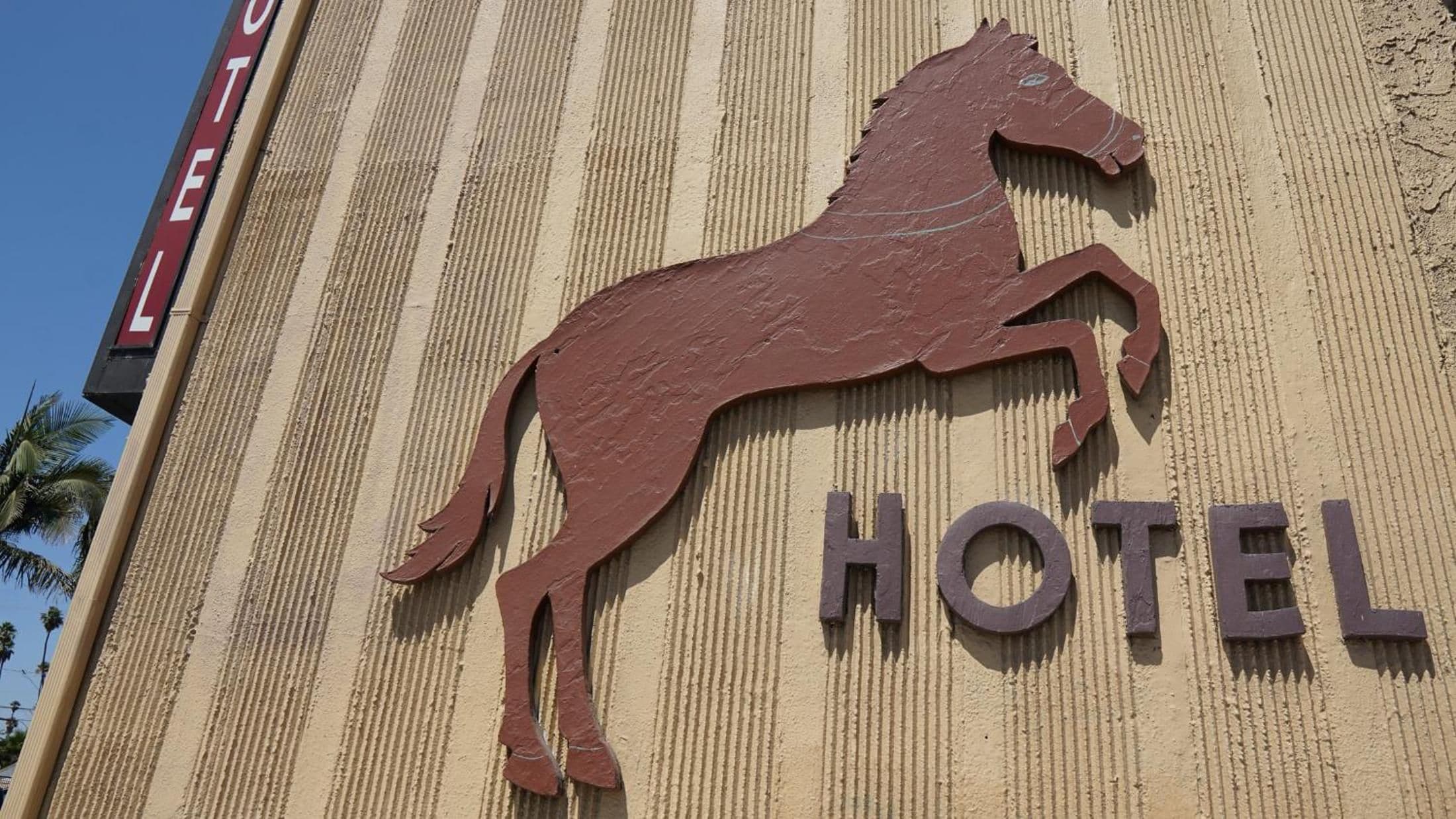 A hotel sign with a horse silhouette and the word 'HOTEL' on a textured wall.