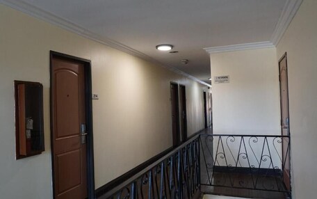 A hotel hallway with doors, a no smoking sign, and a metal railing.