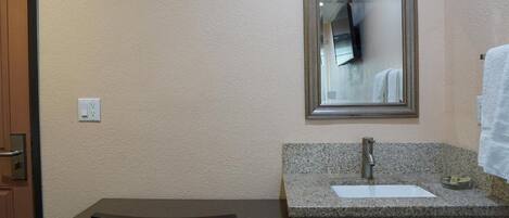 A bathroom with a granite countertop, a sink, a mirror, and a towel rack.