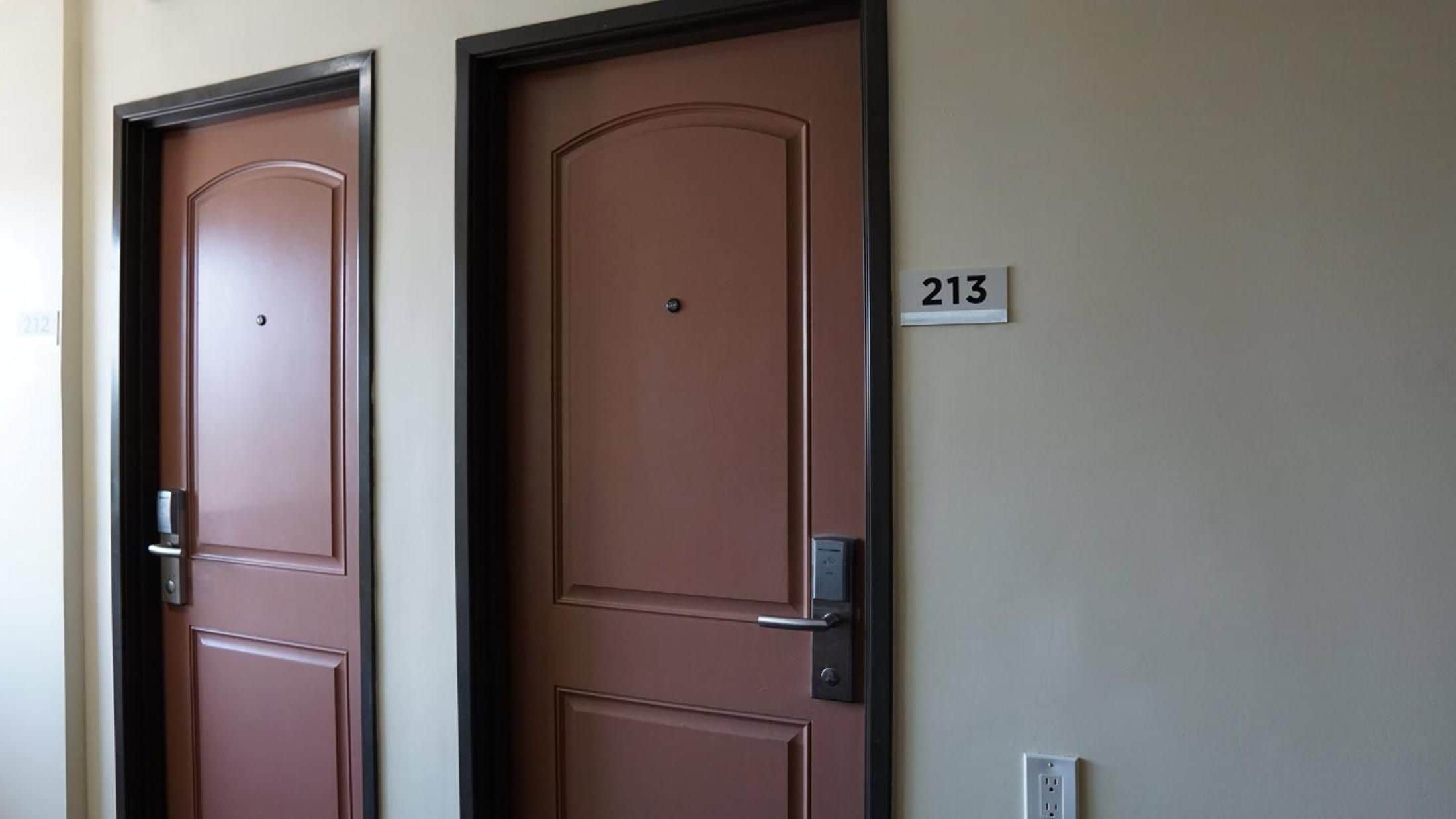 Dos puertas cerradas con un cartel de número arriba, indicando números de habitación.