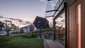 A modern house with a glass facade, a stone wall, and a grassy area.