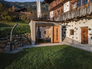 A modern building with a glass door entrance, stone walls, and a wooden balcony. - Holiday Home 'Ufogel' with Mountain View, Wi-Fi and Air Conditioning (Nußdorf/Debant)