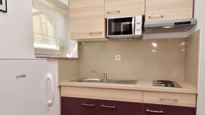 A compact kitchen with a refrigerator, a microwave, a sink, and cabinets.
