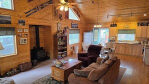 Een gezellig cabin interieur met een open haard, houten wanden, een eethoek en een keuken.