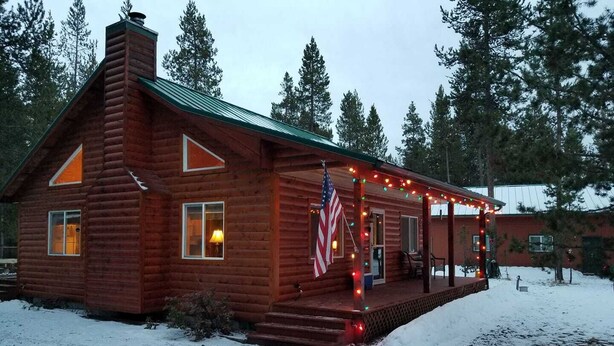 Een blokhut met een veranda, een Amerikaanse vlag en lichtslingers.