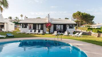 A swimming pool with lounge chairs and a building with a tiled roof.
