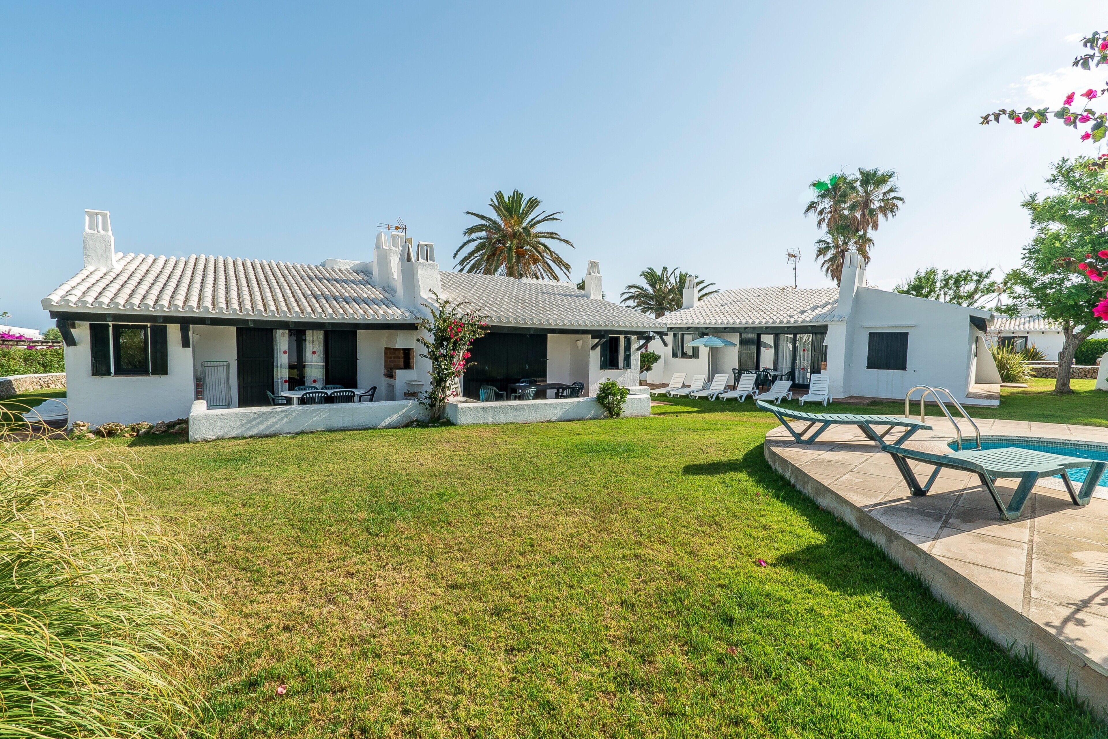 A modern villa with a swimming pool, outdoor seating, and a well-maintained lawn.