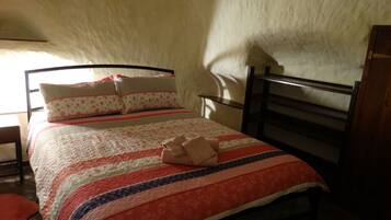 A bed with a patterned bedspread, pillows, and a blanket folded at the foot of the bed.
