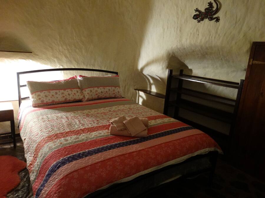 A bed with a patterned bedspread, pillows, and a blanket folded at the foot of the bed.