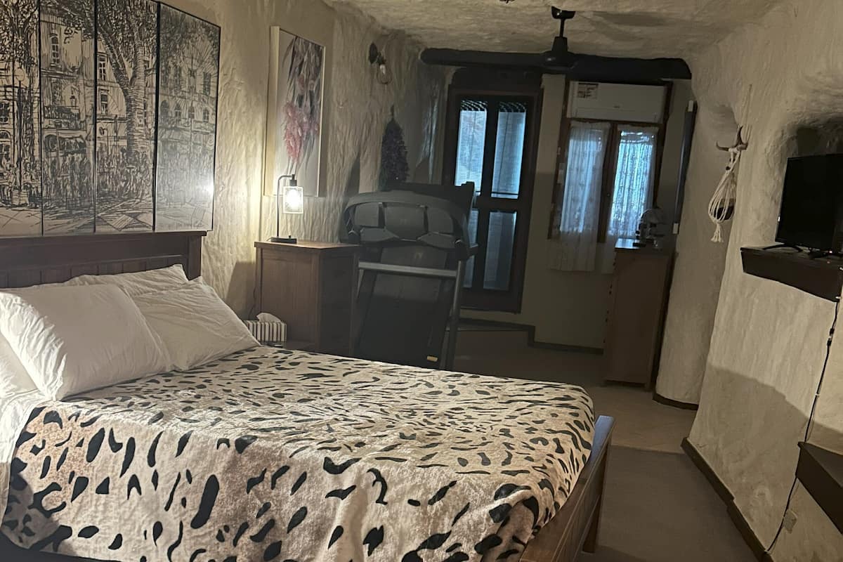 A bedroom with a bed, a chair, a desk, and a television.