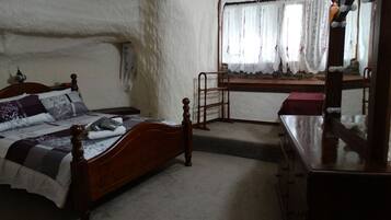 A bedroom with a wooden bed, a dresser, a mirror, and a window with curtains.