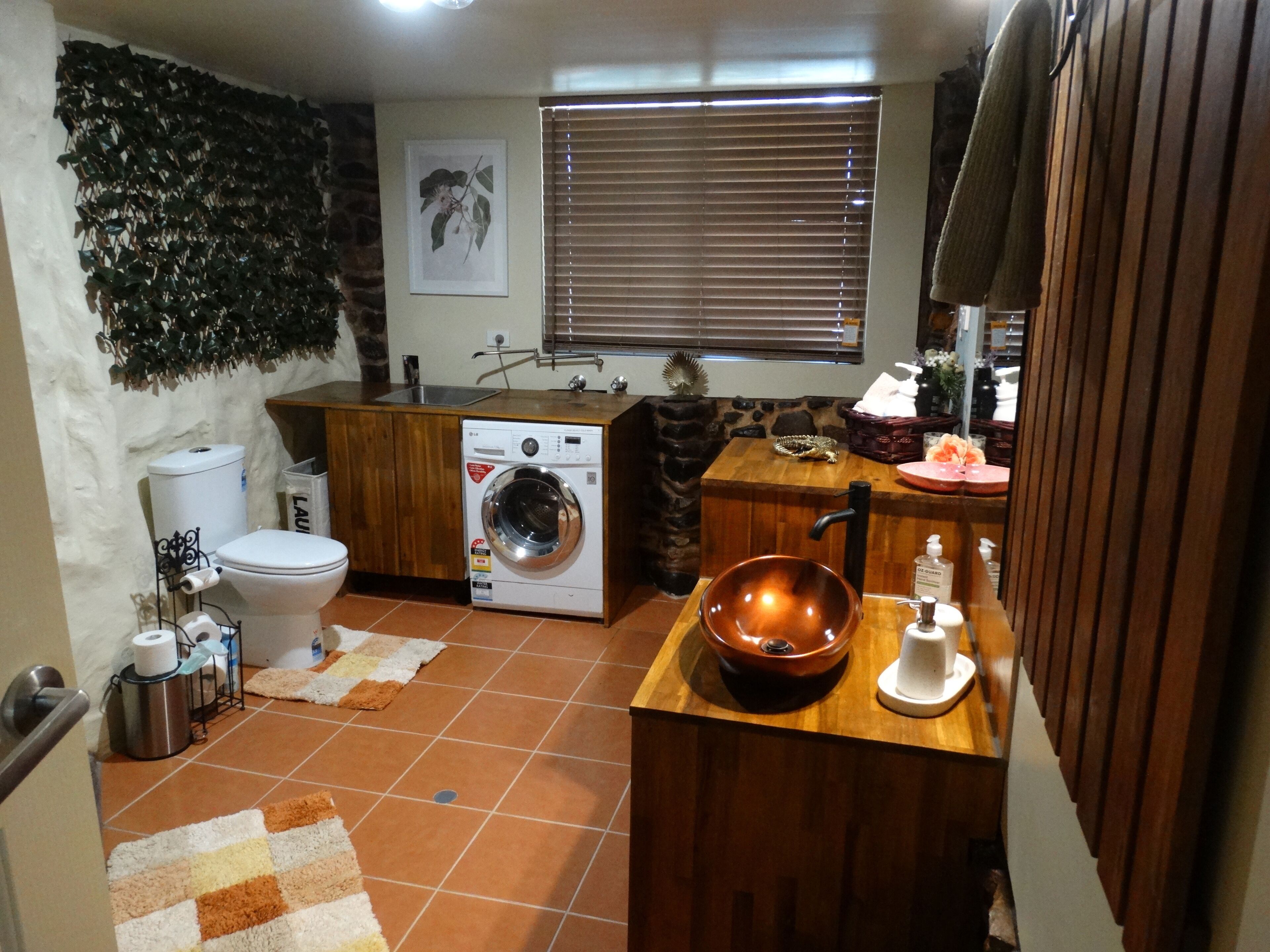 A compact kitchen with a washing machine, a sink, and a wooden countertop.