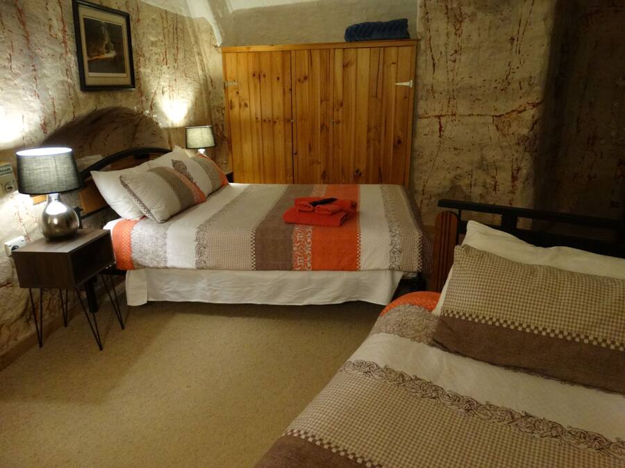 A bedroom with a wooden wardrobe, a bedside table with a lamp, and a bed with striped bedding.