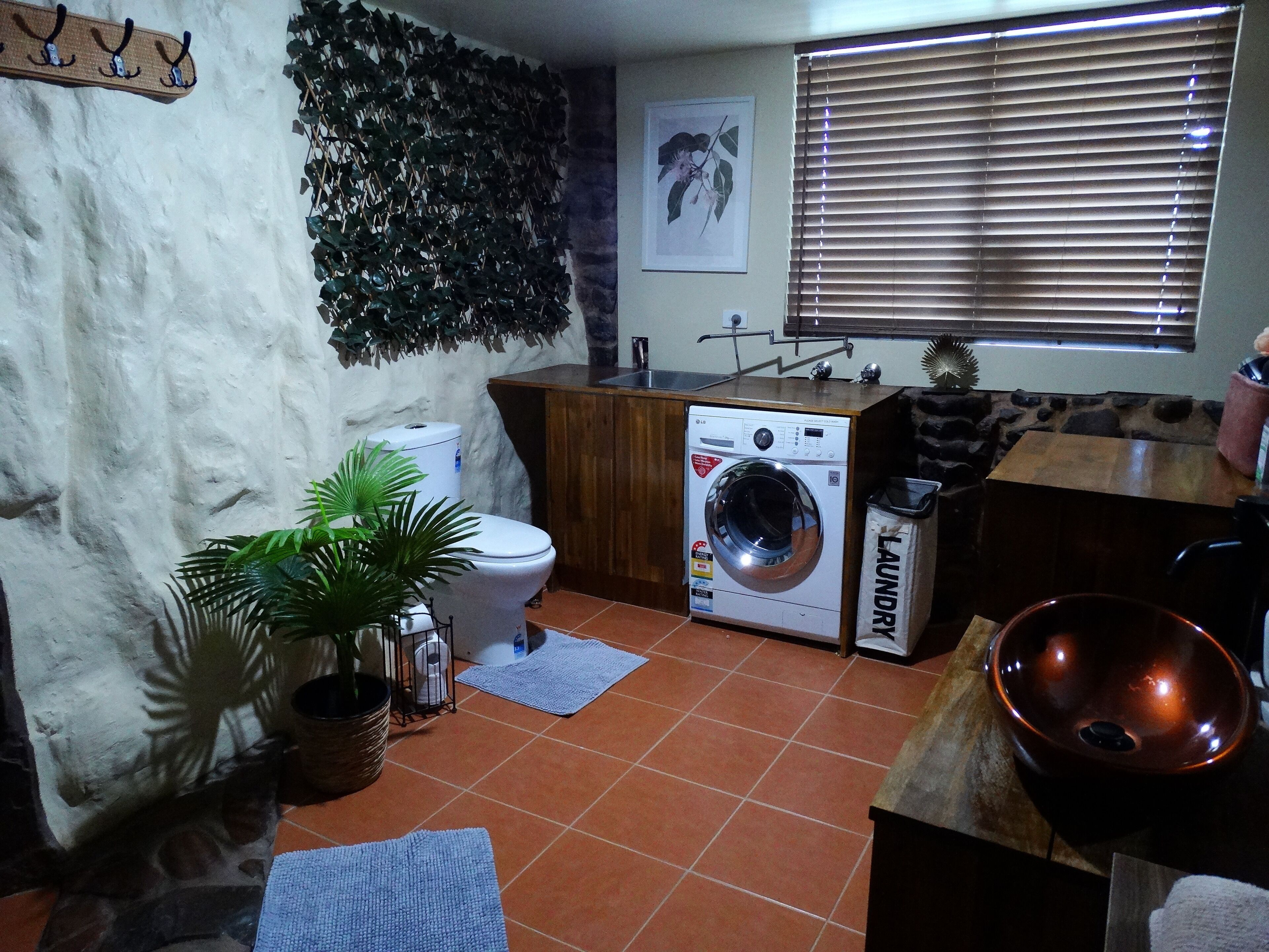 A compact kitchen with a washing machine, a sink, and a countertop with a copper bowl.