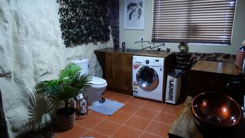 A compact kitchen with a washing machine, a sink, and a countertop with a copper bowl.