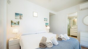 A hotel room with a bed, a nightstand, a lamp, a mirror, and artwork on the wall.
