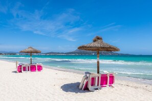 A beach with thatched umbrellas and pink luggage on the sand. - Holiday Apartment Ana Playasol next to the Beach with Sea View (Puerto Alcudia)