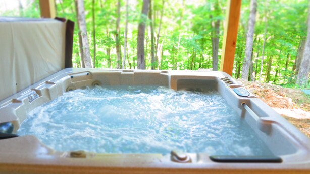 A hot tub with a view of a forest. - Rocky Pine Cabin. Hot Tub, and Pet Friendly! (Nelsonville)