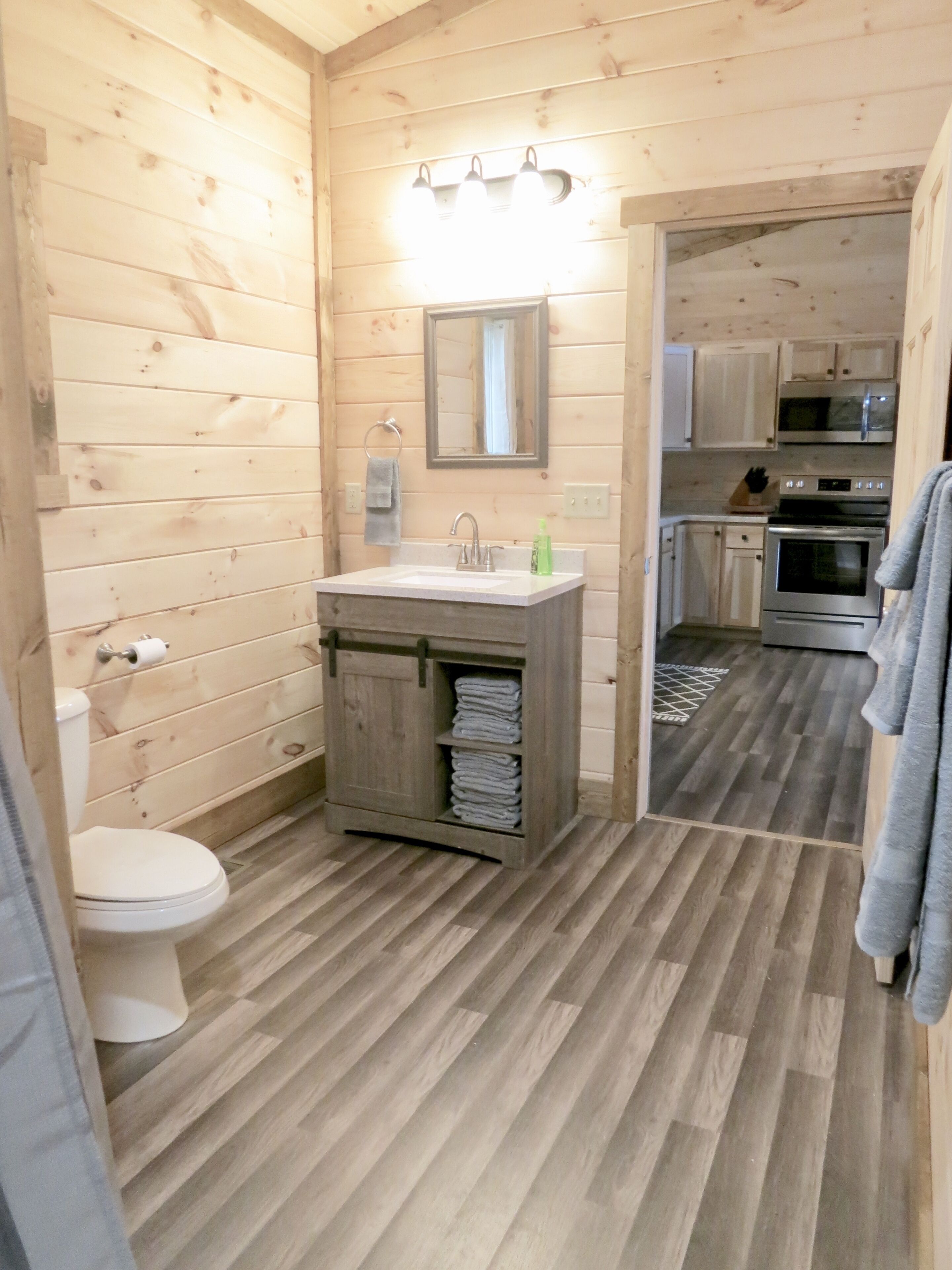 A wooden cabin-style bathroom with a sink, toilet, and a mirror above the sink.