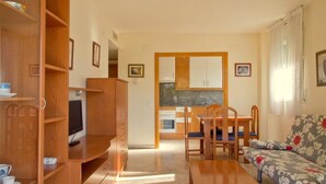 Un espacio habitable compacto con kitchenette, comedor y sofá.